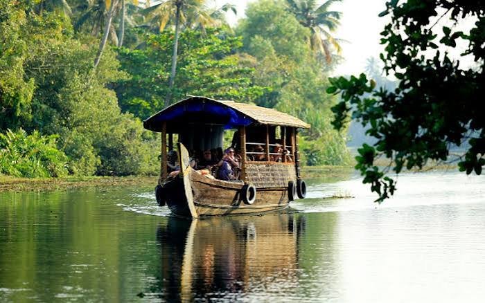 A traditional houseboat gliding through the green Kerala backwaters